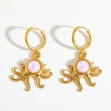 A pair of gold octopus drop earrings with iridescent white opal-like centers.