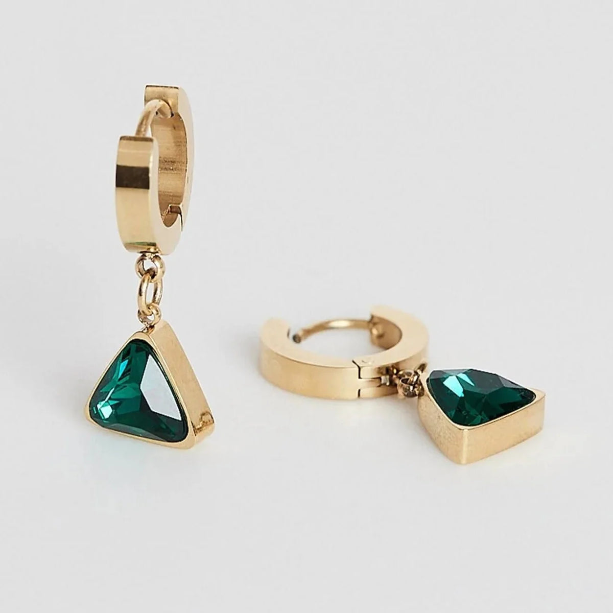 Gold huggie hoop earrings with dangling triangular green gemstone charms.
