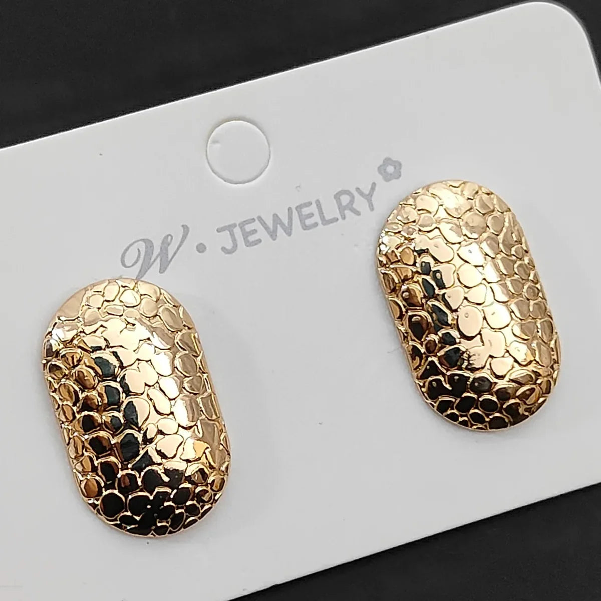 A pair of gold oval stud earrings with a textured, scale-like pattern.
