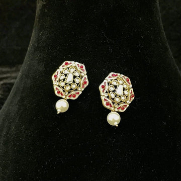 A pair of gold-plated Indian Kundan earrings with red stone accents and white pearl drops, displayed on a black velvet jewelry bust.