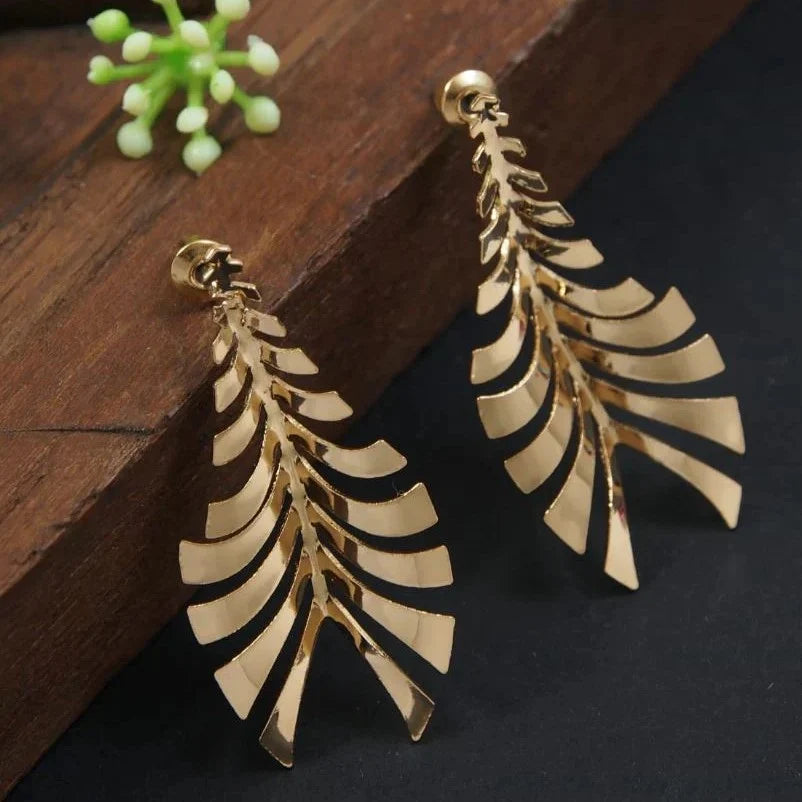 A pair of gold-toned dangle earrings with a layered, leaf-like cutout design.